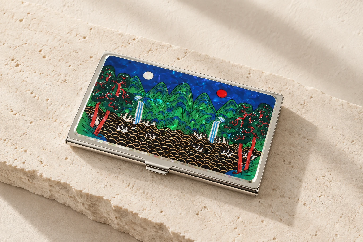 Mother-of-pearl business card case on pale stone.