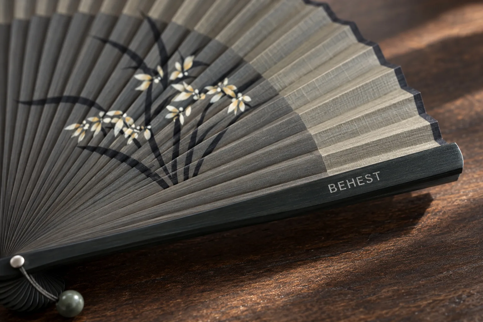 Close view of BEHEST on the dark guard of an open fan with a painted orchid. Design concept.