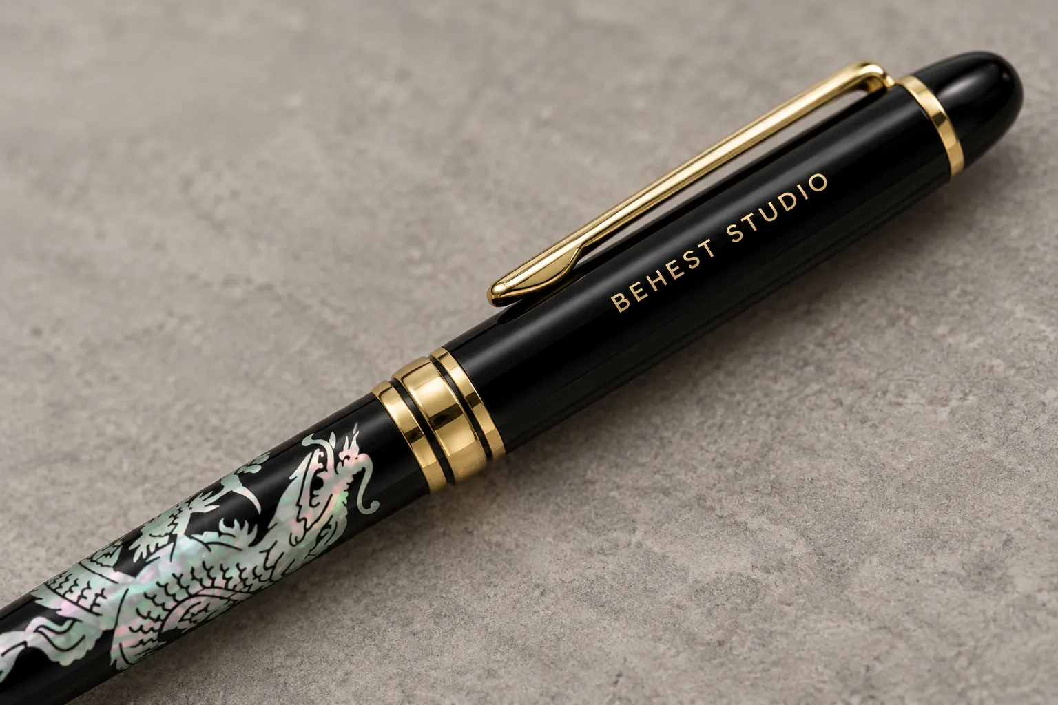 Close view of BEHEST STUDIO engraved on the black upper barrel beside the gold clip. Design concept.