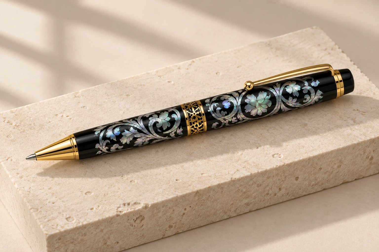 Mother-of-pearl pen with gold-tone trim on pale stone.